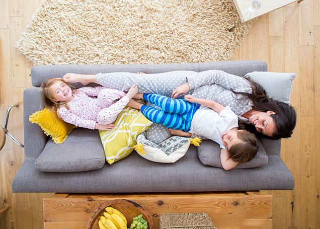 一个女人和两个小孩坐在沙发上享受温暖 